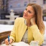 Eine junge Frau mit langen blonden Haaren, sitzt in einem Restaurant und schaut verträumt in den Himmel. Sie macht einen zufriedenen Eindruck, weil Sie ihr Selbstbewusstsein mit dem Programm der unibee Institute gut entwickeln konnte. Sie ist bekleidet mit einer gelben Sommerjacke und einer weiss/grau gestreiften Bluse. In der Hand hält sie einen Blauen Stift und schreibt damit etwas in den Terminkalender. Der Hintergrund ist nur verschwommen zu sehen, damit die Frau im deutlichen Fokus des Bildes steht. Eine junge Frau mit langen blonden Haaren, sitzt in einem Restaurant und schaut verträumt in den Himmel. Sie macht einen zufriedenen Eindruck, weil Sie ihr Selbstbewusstsein mit dem Programm der unibee Institute gut entwickeln konnte. Sie ist bekleidet mit einer gelben Sommerjacke und einer weiss/grau gestreiften Bluse. In der Hand hält sie einen Blauen Stift und schreibt damit etwas in den Terminkalender. Der Hintergrund ist nur verschwommen zu sehen, damit die Frau im deutlichen Fokus des Bildes steht.