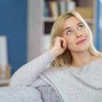 Eine Frau sitzt auf einem Sofa und schaut nach oben. Sie ihrer Mimik zeigt sie deutlich, dass sie mit dem Programm der unibee Institute, ihr Selbstbewusstsein stärken konnte und jetzt in einer guten Balance sich wohl fühlt. Sie hat glatte, lange, blonde Haare und ist bekleidet mit einem hellgrauen Pullover. Im Hintergrund ist verschwommen ein Wohnzimmer zu sehen, welches eine blaue Farbe an der Wand hat. Eine Frau sitzt auf einem Sofa und schaut nach oben. Sie ihrer Mimik zeigt sie deutlich, dass sie mit dem Programm der unibee Institute, ihr Selbstbewusstsein stärken konnte und jetzt in einer guten Balance sich wohl fühlt. Sie hat glatte, lange, blonde Haare und ist bekleidet mit einem hellgrauen Pullover. Im Hintergrund ist verschwommen ein Wohnzimmer zu sehen, welches eine blaue Farbe an der Wand hat.