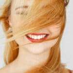 Ein lachendes Gesicht einer hübschen jungen Frau, strahlt starkes Selbstbewusstsein aus. Ihre langen hellblonden Haare wehen Ihr ins Gesicht, sodass das linke Auge nicht zu erkennen ist. Der Hintergrund ist schlicht weiss. Ein lachendes Gesicht einer hübschen jungen Frau, strahlt starkes Selbstbewusstsein aus. Ihre langen hellblonden Haare wehen Ihr ins Gesicht, sodass das linke Auge nicht zu erkennen ist. Der Hintergrund ist schlicht weiss.