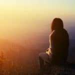 Eine Frau sitzt auf einem Berggipfel und genießt die Ruhe. Dadurch kann sie ihr Selbstvertrauen stärken, indem sie lange Zeit alleine nachdenkt. Im Hintergrund sind viele Berghügel zu sehen, es ist Abendrot mit Nebel. Eine Frau sitzt auf einem Berggipfel und genießt die Ruhe. Dadurch kann sie ihr Selbstvertrauen stärken, indem sie lange Zeit alleine nachdenkt. Im Hintergrund sind viele Berghügel zu sehen, es ist Abendrot mit Nebel.