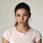 Eine junge Frau mit langen schwarzen Haaren, zieht ihre linke Augenbraun hoch und zeigt durch diese Mimik, dass ihr das Programm der unibee Institute geholfen hat, ein gutes Selbstbewusstsein aufbauen zu können. Ihre Gestik zeigt ebenso, dass sie jetzt viele Dinge entspannt vorüberziehen lässt. Sie ist bekleidet mit einem rosa T-shirt. Der Hintergrund ist neutral weiss. Eine junge Frau mit langen schwarzen Haaren, zieht ihre linke Augenbraun hoch und zeigt durch diese Mimik, dass ihr das Programm der unibee Institute geholfen hat, ein gutes Selbstbewusstsein aufbauen zu können. Ihre Gestik zeigt ebenso, dass sie jetzt viele Dinge entspannt vorüberziehen lässt. Sie ist bekleidet mit einem rosa T-shirt. Der Hintergrund ist neutral weiss.