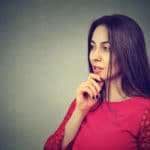 Eine Frau mit langen schwarzen Haaren schaut sehr selbstbewusst in die Ferne. Sie hält dabei ihren rechten Arm unter dem Kopf, denn diese Mimik soll Stärke und Sicherheit in der Gefühlsbalance ausdrücken. Sie ist bekleidet mit einem roten Pullover. Der Hintergrund ist grau. Eine Frau mit langen schwarzen Haaren schaut sehr selbstbewusst in die Ferne. Sie hält dabei ihren rechten Arm unter dem Kopf, denn diese Mimik soll Stärke und Sicherheit in der Gefühlsbalance ausdrücken. Sie ist bekleidet mit einem roten Pullover. Der Hintergrund ist grau.