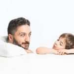 Ein Mann sitzt mit seinem kleinen Sohn an einem Tisch und unterhält sich mit ihm. Der Vater hört intensiv zu um das Selbstbewusstsein des kindes zu stabilisieren. Der Hintergrund ist glänzend weiss ohne weitere Elemente. Der Mann hat kurze graue Haare und trägt einen Vollbart. Bekleidet sind beide mit einem weissen Pullover. Ein Mann sitzt mit seinem kleinen Sohn an einem Tisch und unterhält sich mit ihm. Der Vater hört intensiv zu um das Selbstbewusstsein des kindes zu stabilisieren. Der Hintergrund ist glänzend weiss ohne weitere Elemente. Der Mann hat kurze graue Haare und trägt einen Vollbart. Bekleidet sind beide mit einem weissen Pullover.