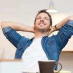 Ein Mann sitzt auf einem Stuhl, hat beide Arme hinter dem Kopf verschränkt und ist nach hinten gelehnt. Er lächelt dabei und zeigt mit seiner Gestik und Mimik, dass er ein starkes Selbstbewusstsein besitzt und dieses auch auslebt. Er hat kurze braune Haare, einen 3 Tage Bart und ist bekleidet mit einem bleuen Jeanshemd und weissen T-shirt. Im Vordergrund ist eine braune Tasse zu sehen und der Hintergrund ist schlicht weiss gehalten. Ein Mann sitzt auf einem Stuhl, hat beide Arme hinter dem Kopf verschränkt und ist nach hinten gelehnt. Er lächelt dabei und zeigt mit seiner Gestik und Mimik, dass er ein starkes Selbstbewusstsein besitzt und dieses auch auslebt. Er hat kurze braune Haare, einen 3 Tage Bart und ist bekleidet mit einem bleuen Jeanshemd und weissen T-shirt. Im Vordergrund ist eine braune Tasse zu sehen und der Hintergrund ist schlicht weiss gehalten.