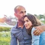 Ein Paar mitleren Alters steht auf einer grünen Wiese. Der Mann hält seine Frau im Arm und lächeln leicht und wirken entspannt. Sie zeigen mit ihrer Mimik und Gestik Gefühle der Harmonie. Ser Mann zeigt deutlich ein Selbstbewusstses auftreten, so als würde er seine Frau jederzeit beschützen können. Der Mann hat keine Haare und die Frau hat lange dunkelbraune gewellte Haare. Sie ist mit einem hellblauen Pullover bekleidet und er trägt ein blau/weiss kariertes Freizeithemd. Ein Paar mitleren Alters steht auf einer grünen Wiese. Der Mann hält seine Frau im Arm und lächeln leicht und wirken entspannt. Sie zeigen mit ihrer Mimik und Gestik Gefühle der Harmonie. Ser Mann zeigt deutlich ein Selbstbewusstses auftreten, so als würde er seine Frau jederzeit beschützen können. Der Mann hat keine Haare und die Frau hat lange dunkelbraune gewellte Haare. Sie ist mit einem hellblauen Pullover bekleidet und er trägt ein blau/weiss kariertes Freizeithemd.