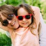 Eine Mutter mit ihrer Tochter strahlen lässig in die Kamera. Beide haben das Programm der unibee Institute zum Selbstbewusstsein stärken genutzt um eine gute Lebensbalance zu bekommen. Mit ihrer Mimik strahlen beide ein gutes Lebensgefühl aus. Beide tragen eine Sonnenbrille und haben lange hellbraune Haare. Bekleidet ist die Frau mit einer weissen Jeansjacke und das Mädchen trägt einen hellrosa Pullover. Im Hintergrund ist ein Naturpark mit vielen blühenden Pflanzen zu sehen. Eine Mutter mit ihrer Tochter strahlen lässig in die Kamera. Beide haben das Programm der unibee Institute zum Selbstbewusstsein stärken genutzt um eine gute Lebensbalance zu bekommen. Mit ihrer Mimik strahlen beide ein gutes Lebensgefühl aus. Beide tragen eine Sonnenbrille und haben lange hellbraune Haare. Bekleidet ist die Frau mit einer weissen Jeansjacke und das Mädchen trägt einen hellrosa Pullover. Im Hintergrund ist ein Naturpark mit vielen blühenden Pflanzen zu sehen.