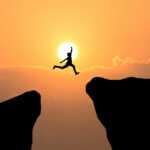 Burnout Behandlung durhc Hypnose wiirkt. Die Person ist glücklich und springt über den Felsen